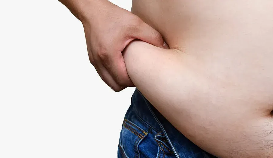 A man grabbing a fist full of fat on his waist. 