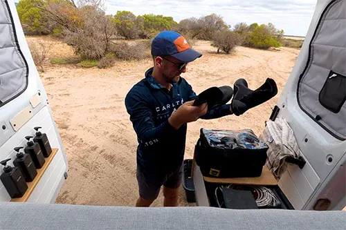 Organising fishing tackle and gear from campervan storage at remote beach
