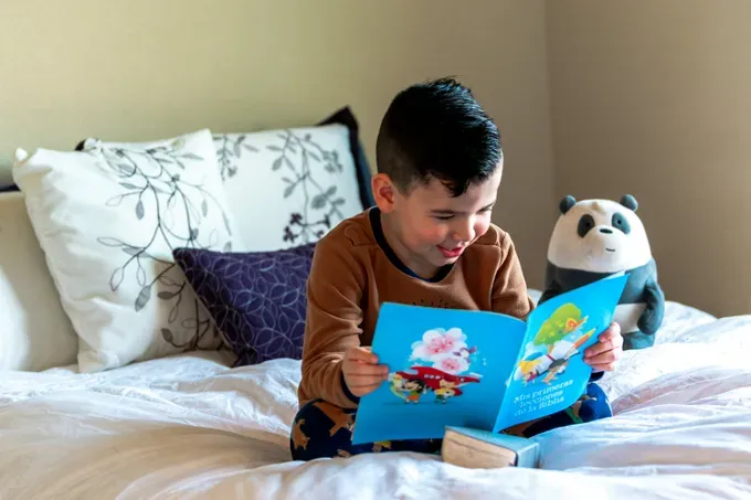 boy in a bed reading a book