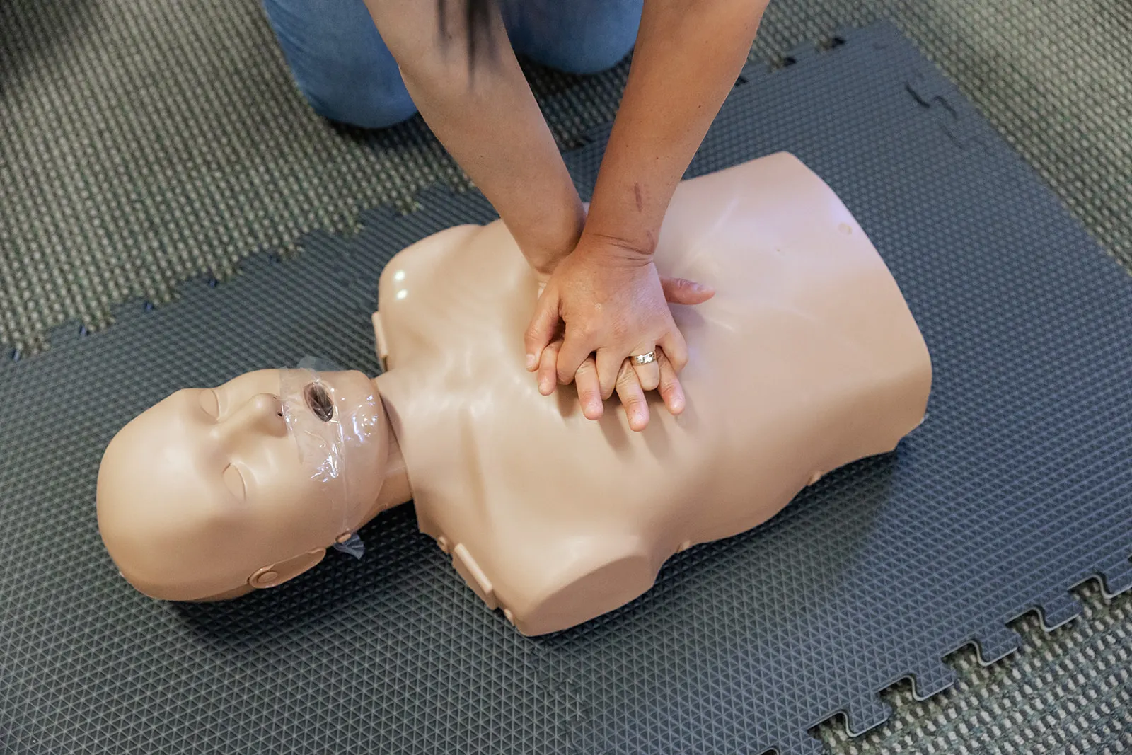 CPR Class student doing CPR on a manikin on the floor at Hospital Med Supply in Cincinnati, OH.