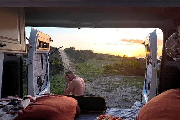 Outdoor shower at the rear of a campervan used for off-grid washing without an internal bathroom