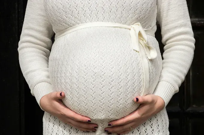 Pregnant woman with hands resting on her belly, showcasing a loving and protective gesture.