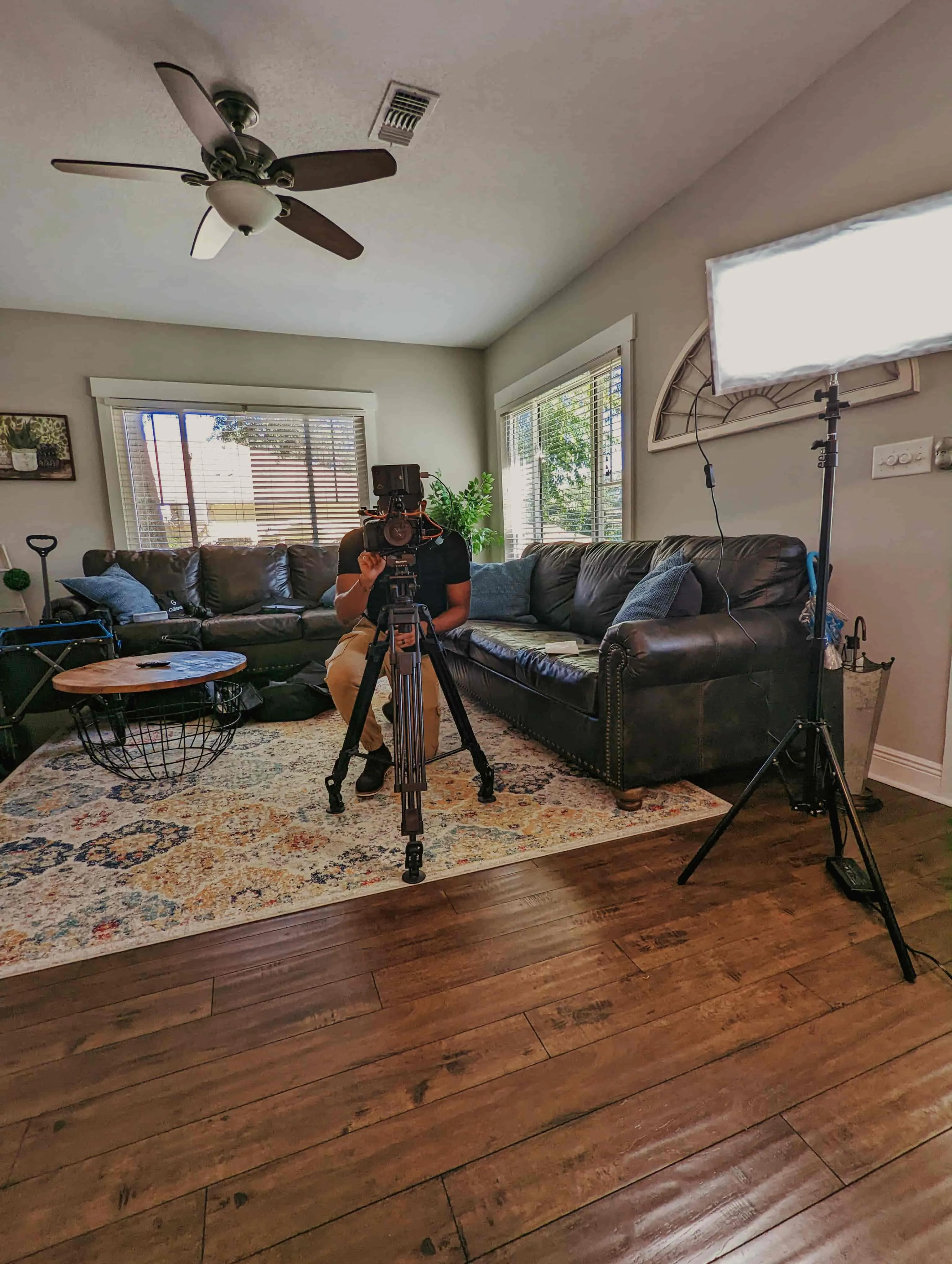 a man operating a blackmagic pocket camera in a living room with bright windows