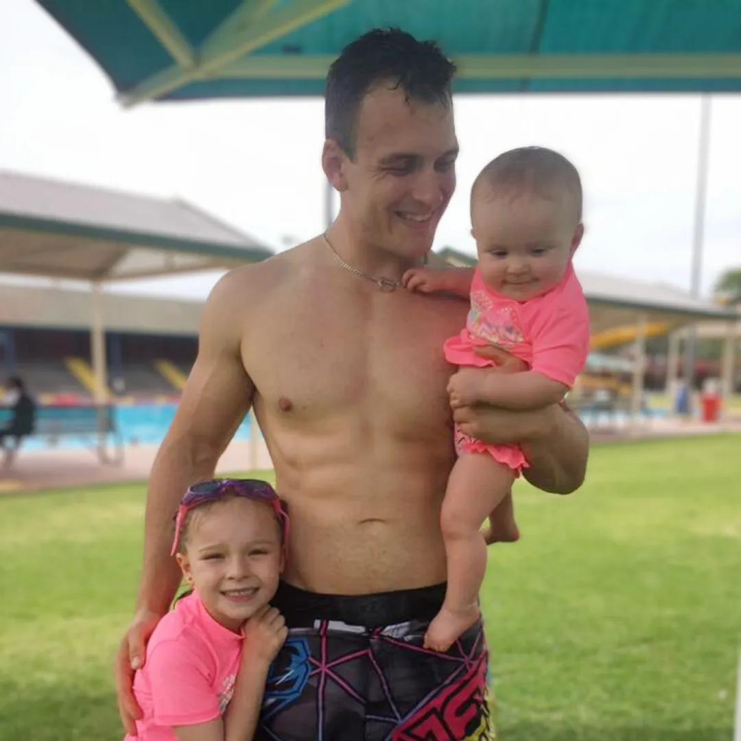 Coach Peter Brown proudly holding his daughters at the local pool