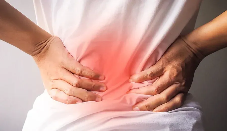 A woman holding lower back with a reddish hue emanating from it indicating lower back pain. 