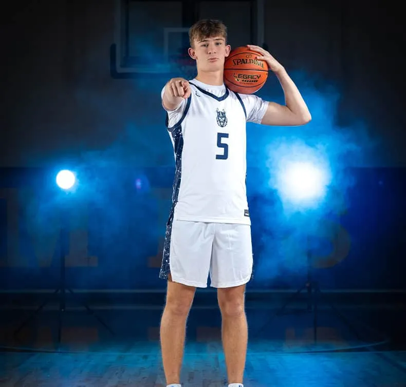 Basketball player in white jersey number 5 with Spalding Legacy ball, dramatic blue lighting and smoke effects in gymnasium, sports portrait