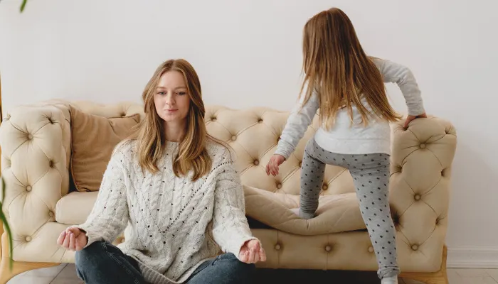 A mom trying to do yoga while her daughter is running around.