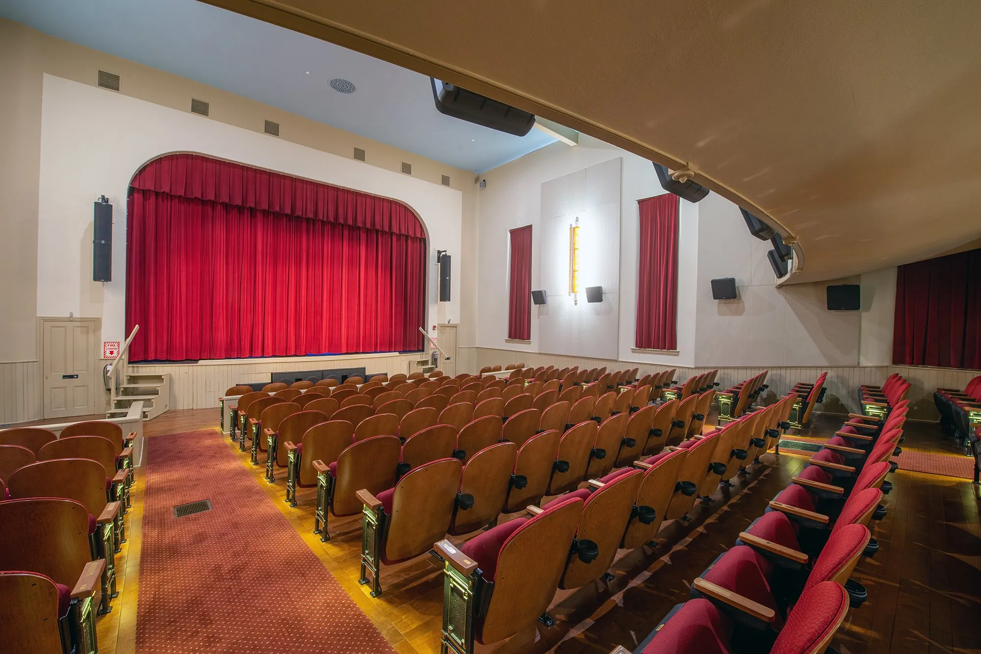 small theater with red carpet and a red curtain on the stage