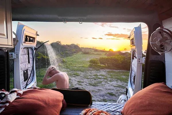 Outdoor shower at the rear of a campervan used for off-grid washing without an internal bathroom