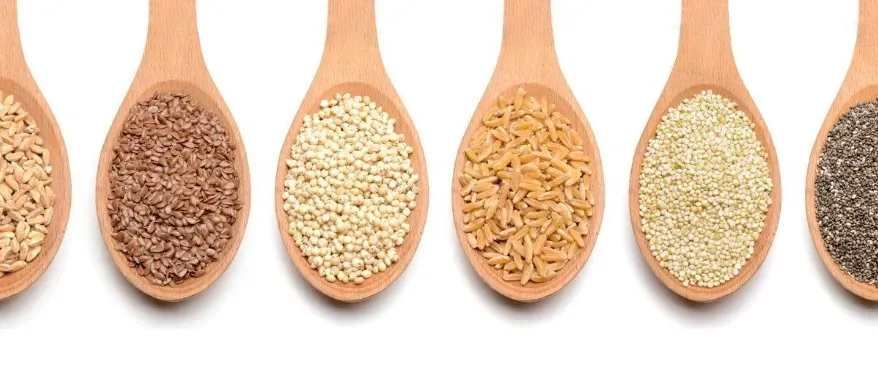 Various ancient grains in wooden spoons.