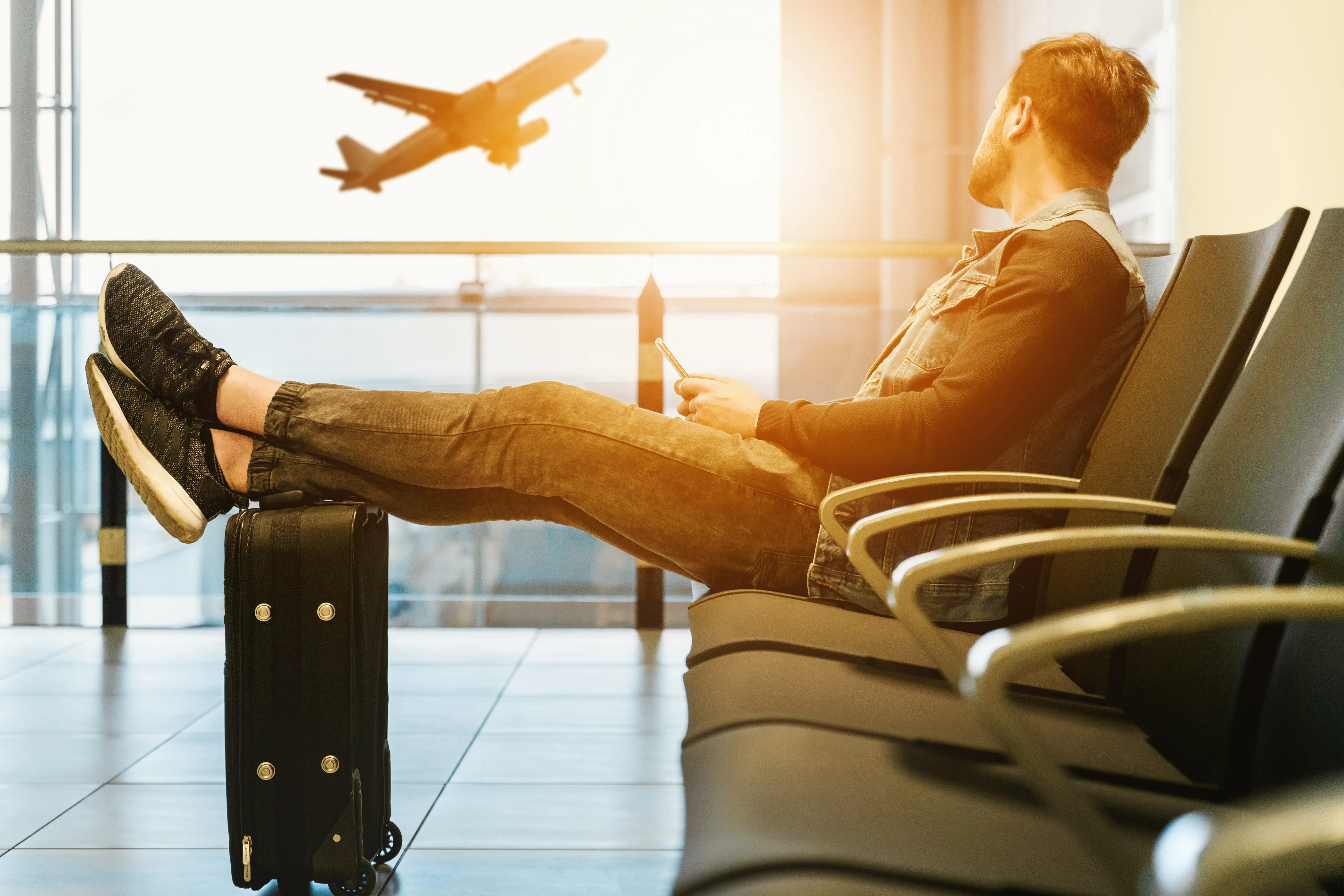 Man sitting in airport watching an airplane takeoff