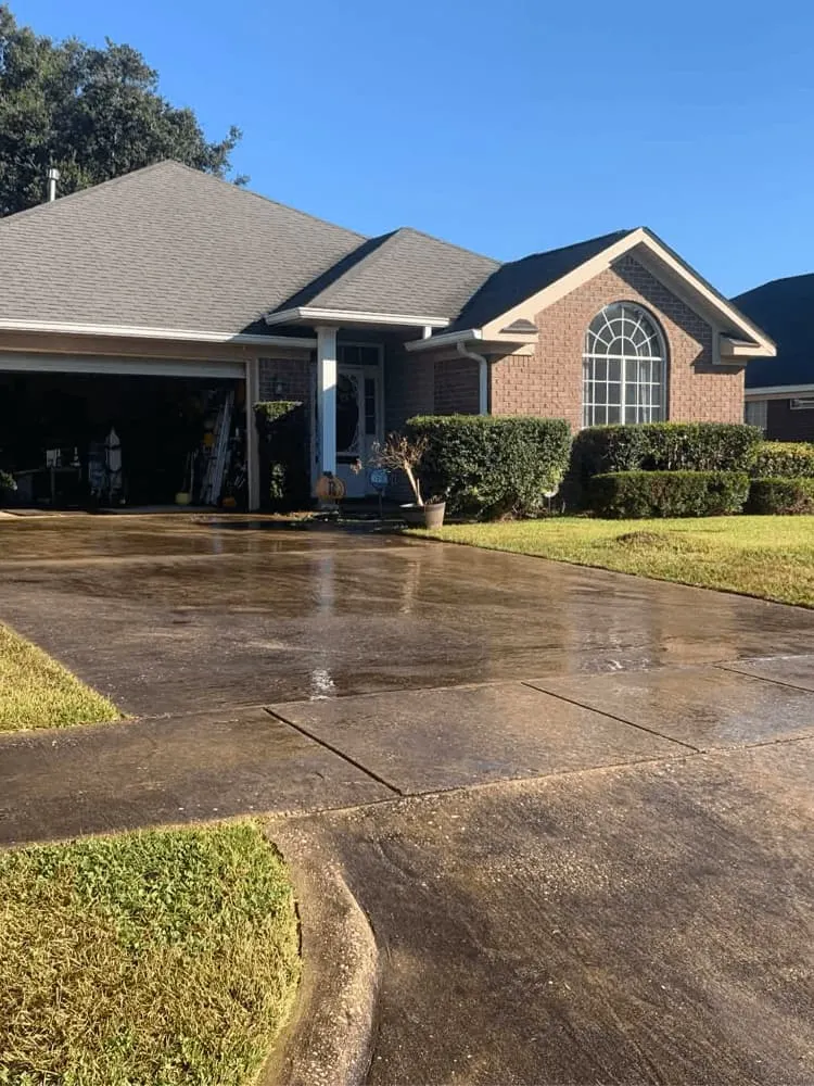 <alt=“Before driveway pressure washing in Dawes, Mobile County, Alabama showing heavy dirt buildup and dark staining across residential concrete driveway.”>