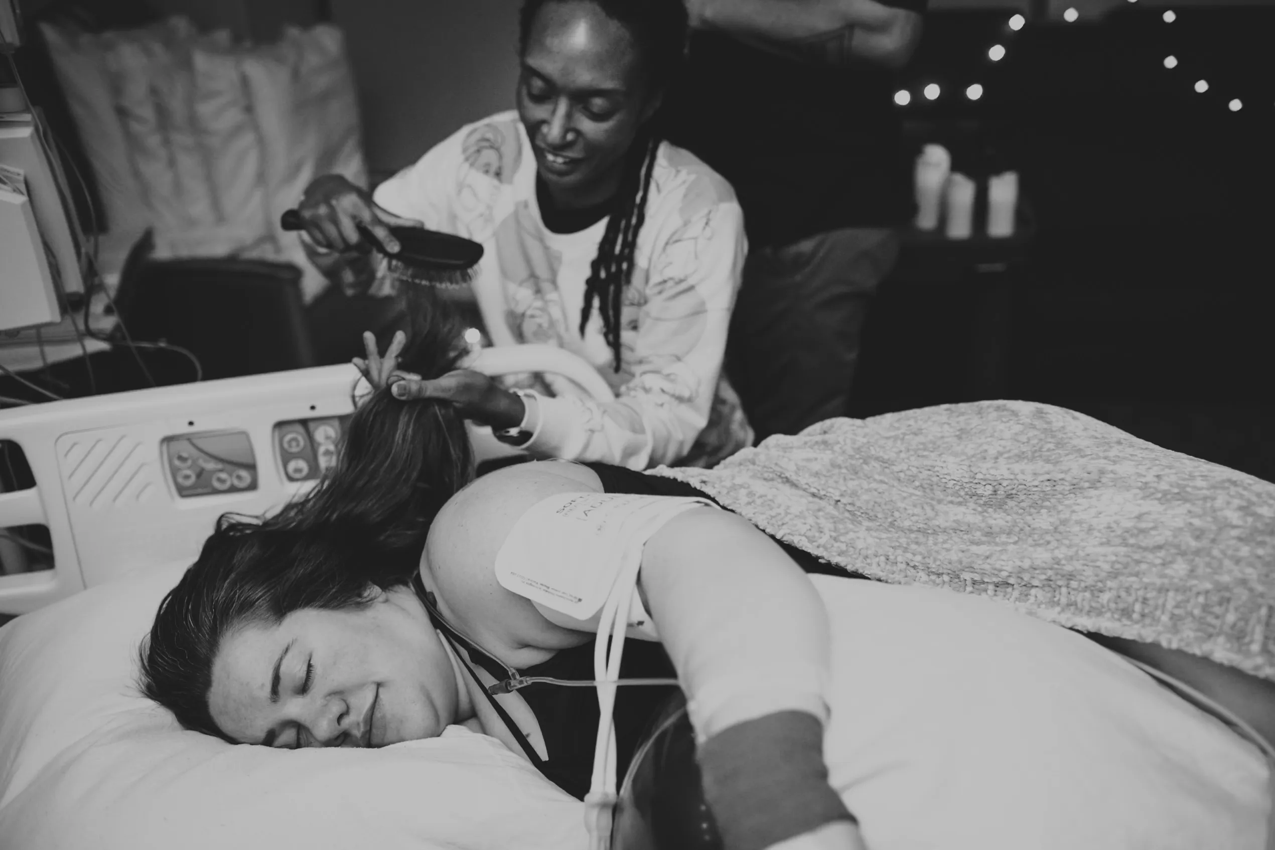 doula brushing client's hair while client is resting in labor. Photos by Colorado Springs Birth Photographer Danica Donnelly