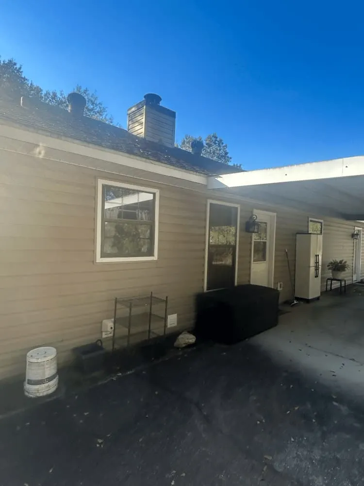 <alt=“Before exterior house cleaning in Mobile County Alabama showing dirty siding and stained concrete patio.”>