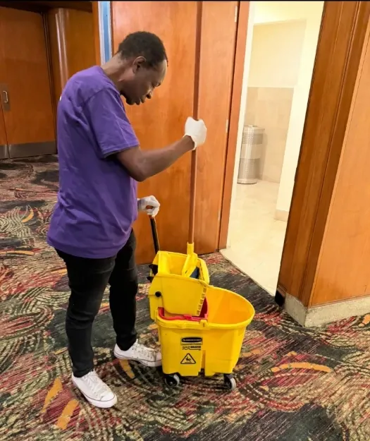 Professional house cleaners from One Way Cleaning Services cleaning a living room in Miami, dusting shelves and sanitizing surfaces