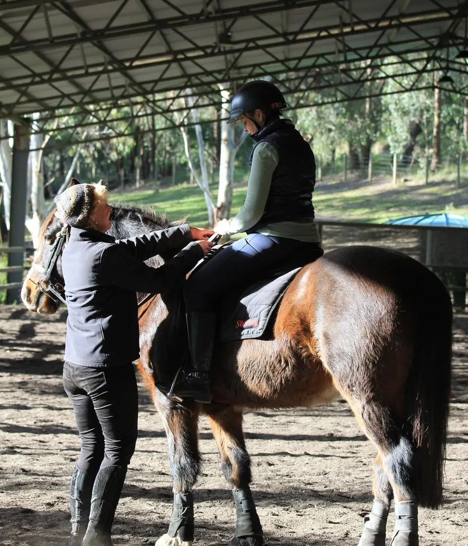 Leanne guiding a beginner rider through how to hold her reins