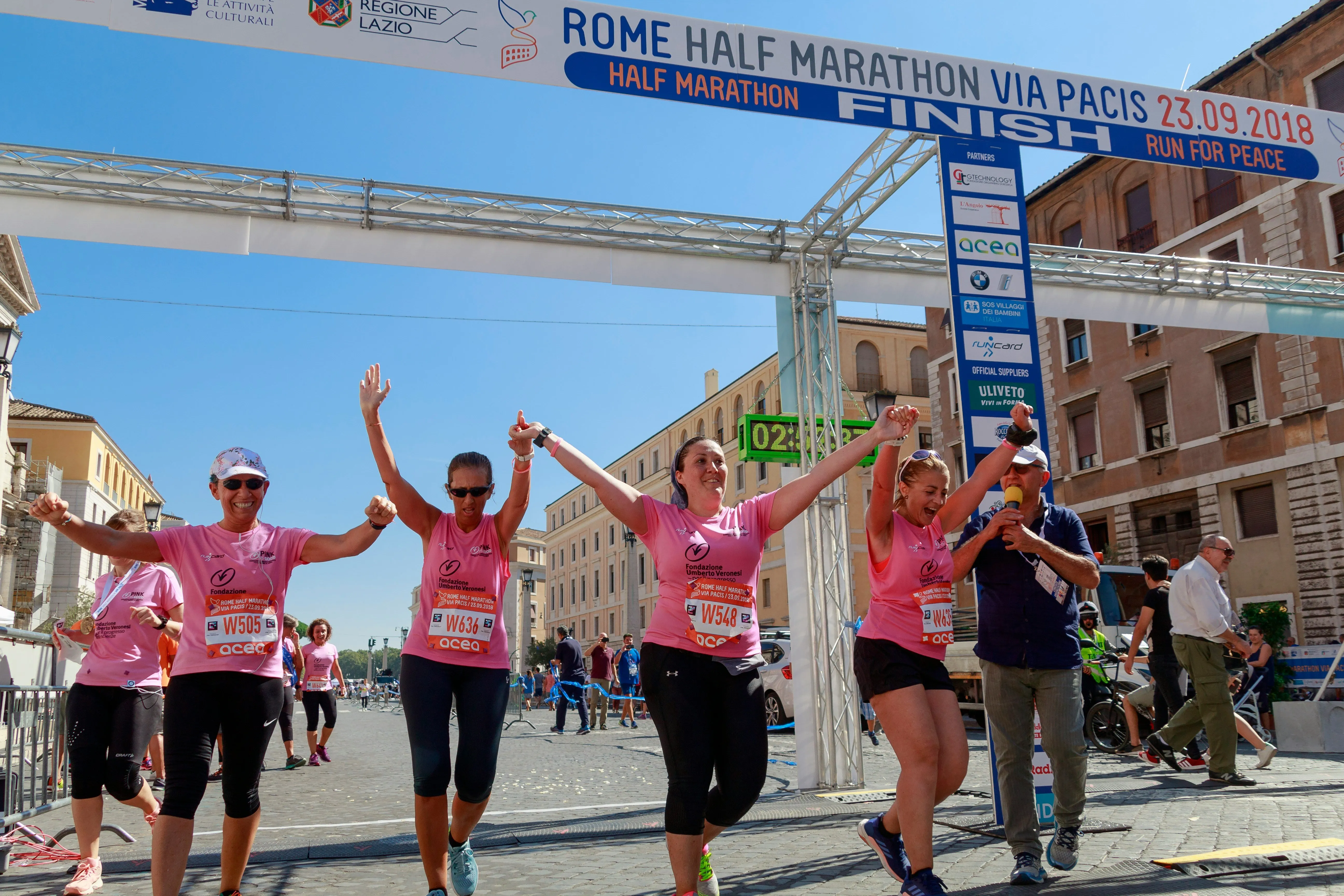 5 women cross the finish line together at a marathon