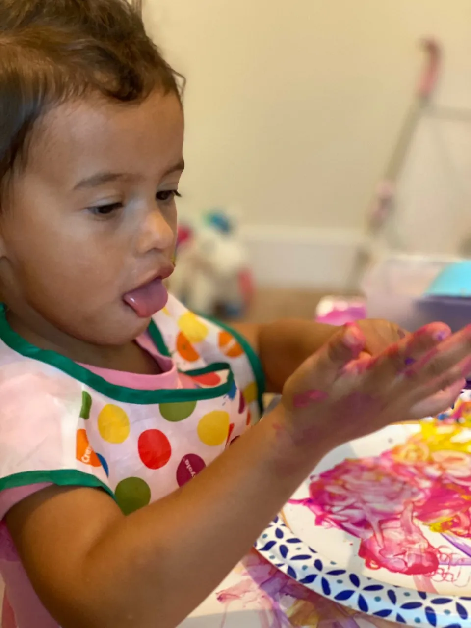 Toddler finger painting with multiple colors