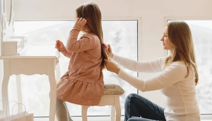 A mom listening to her daughter and doing her hair