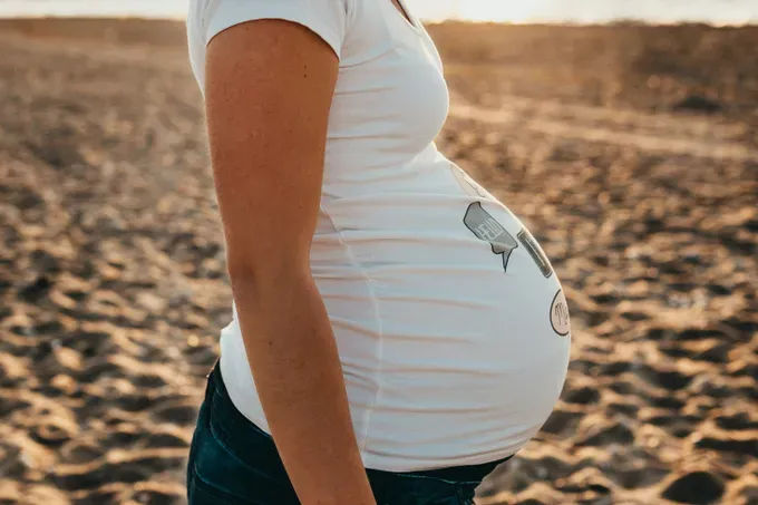 Close-up of a pregnant woman’s belly, showcasing the beautiful roundness of the baby bump.