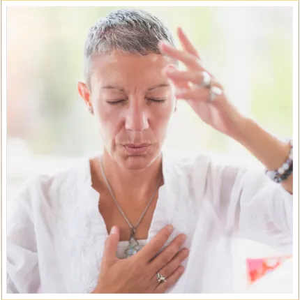 Gray haired women in meditation with hand over her heart