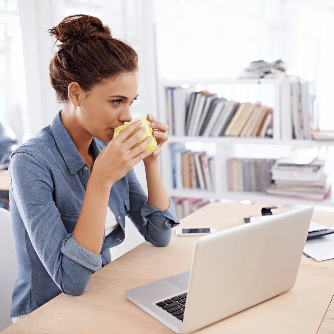 woman having coffee while working on laptop 