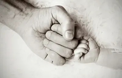 Adult hand fist bumping infant hand