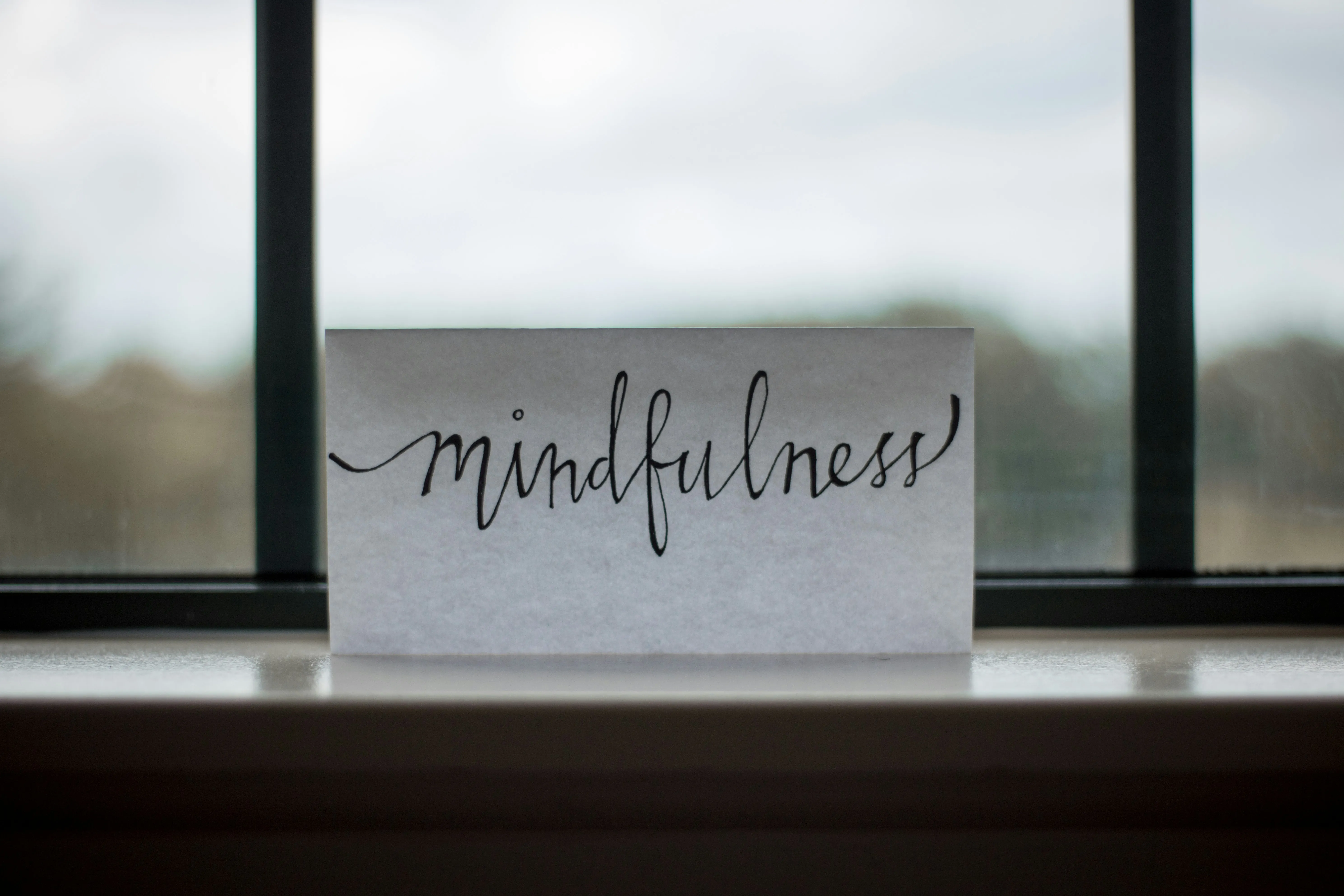 handwritten note that says 'mindfulness'on shelf against window