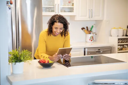Woman at kitchen counter holding a tablet
