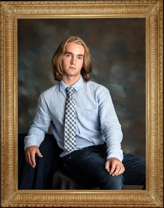 Portrait of Reid who is a young man in a dress shirt and tie leaning to the side on his arm. 