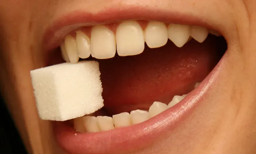 a woman with a sugar cube between her teeth.