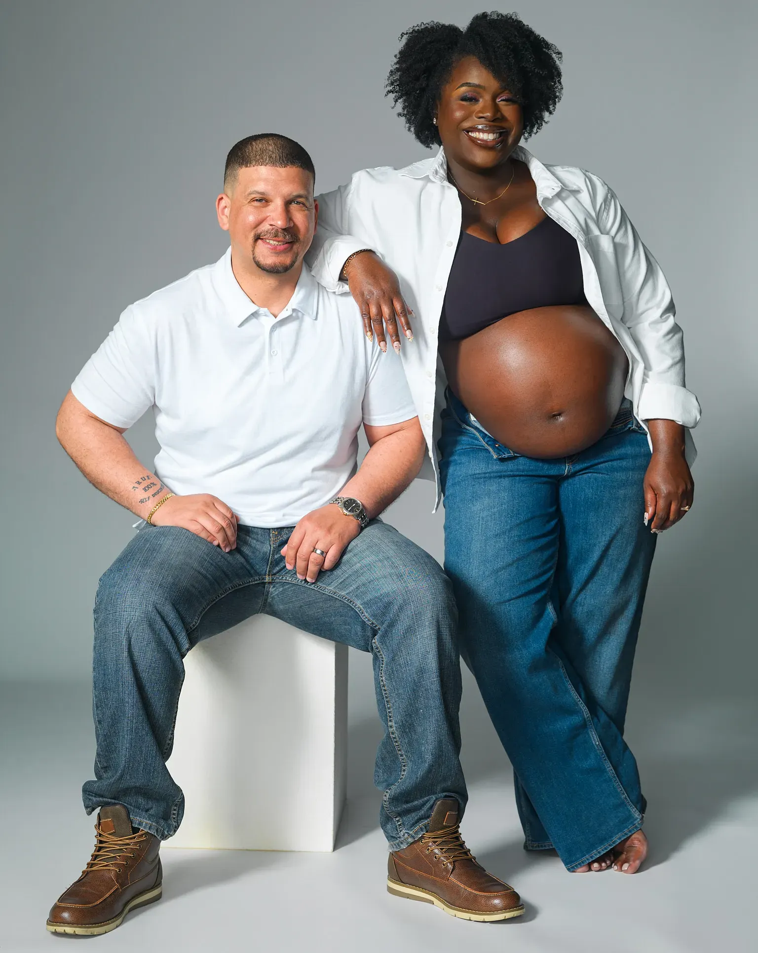 Neutral toned maternity portrait of Asian woman covered by a white sheet posed in front of a taupe background