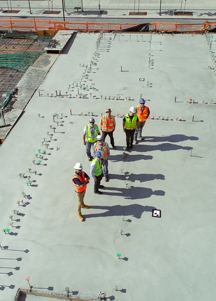 image of arm and hand holding a concrete trowel on a concrete wall as if flattening surface