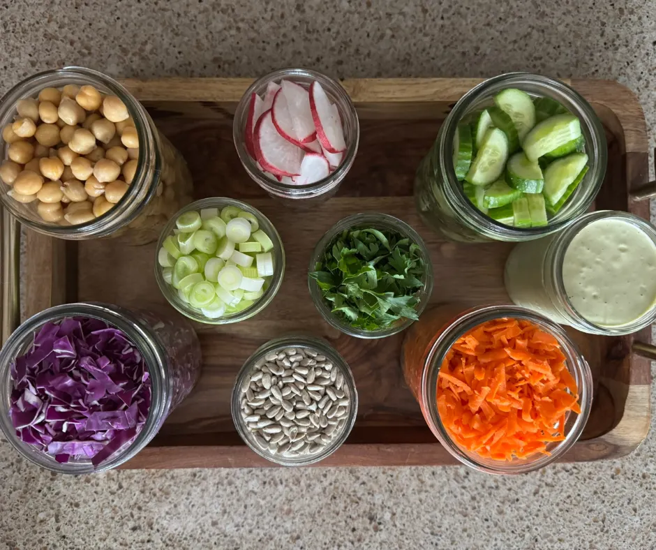 Prep-ahead salad ingredients stored in jars for the Lemon Herb Chickpea Crunch Bowl.