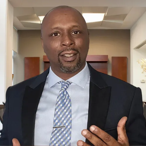 Troilus J. Moss speaking directly to the audience, waist‑up, making an engaged hand gesture while explaining the Digital Asset Entrepreneur movement.