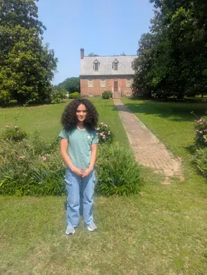 Cadence Hodge, Preservation Virginia summer intern in front of the manor house at Smith's Fort in Surry Virginia