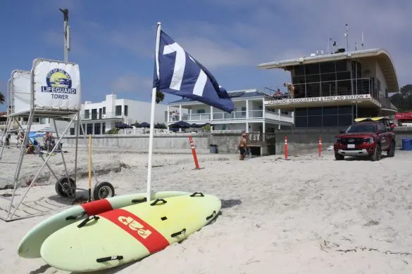 View of the lifeguard station and some paddles boards on the sand.