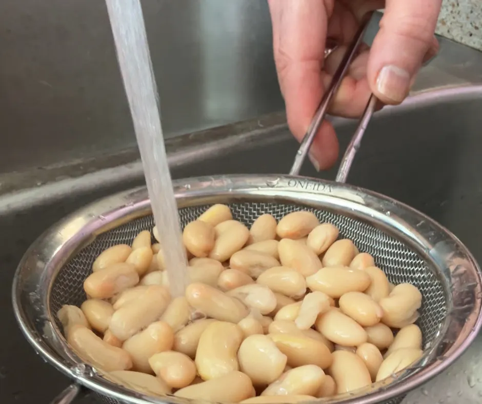 Rinsing canned white beans in a colander under running water for easy meal prep