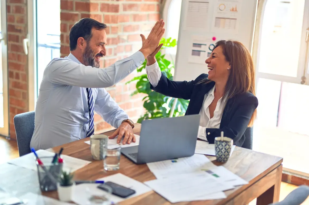Business workers giving each other a high-five for using a sales funnel to locate business leads.