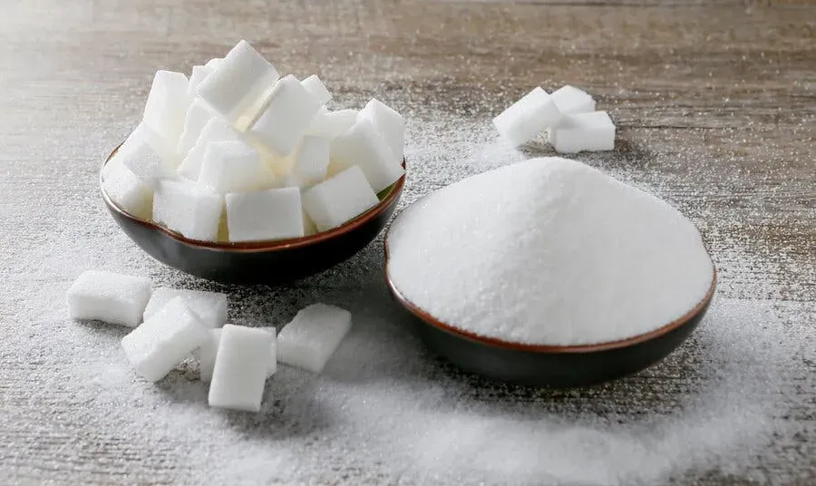 One bowl with sugar cubes next to a bowl of granulated sugar