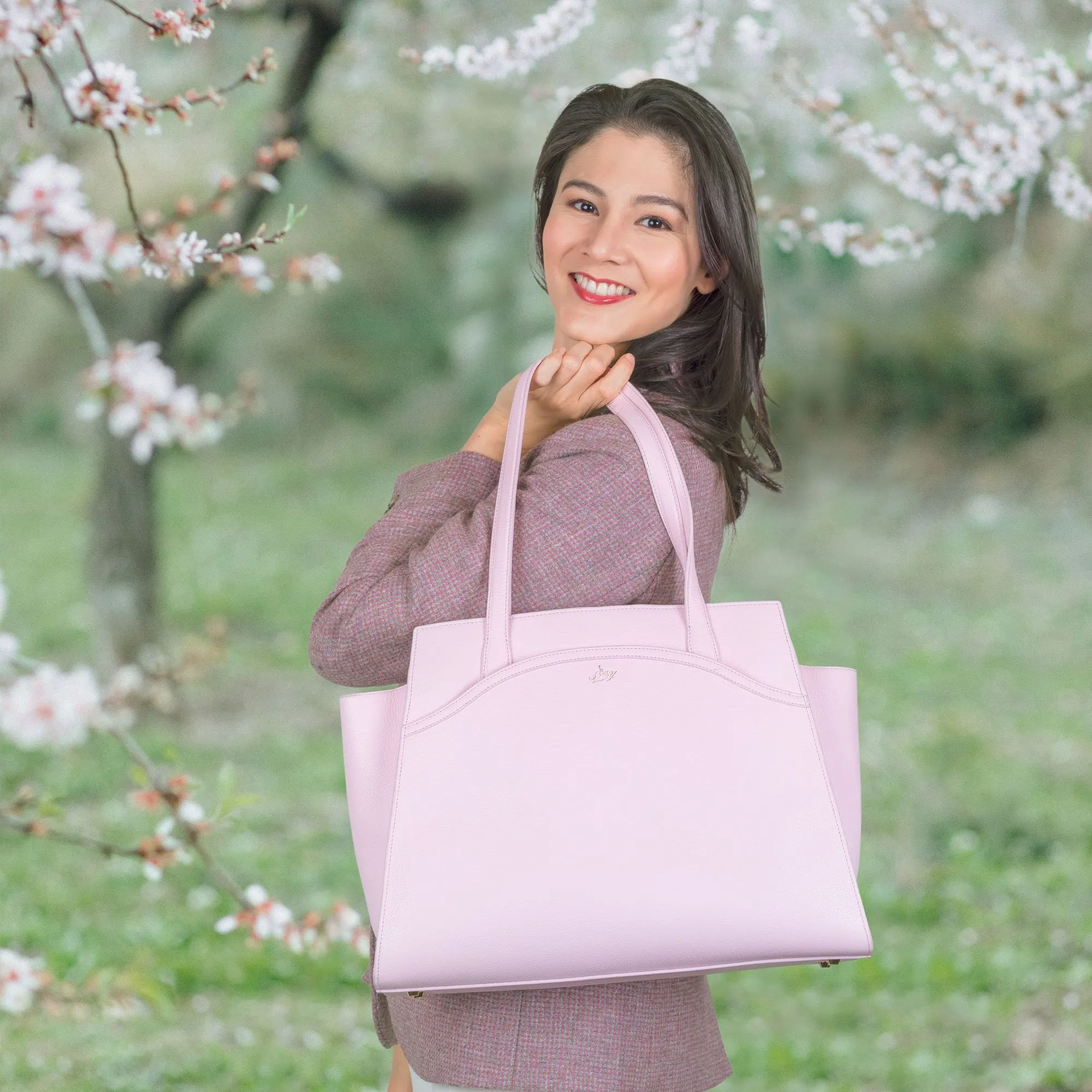 An elegant lady is wearing a blush pink Tang Dynasty Grace Tote, a bag that is inspired by Tang Dynasty, designed by Shen Yun Collections, made in Spain. 