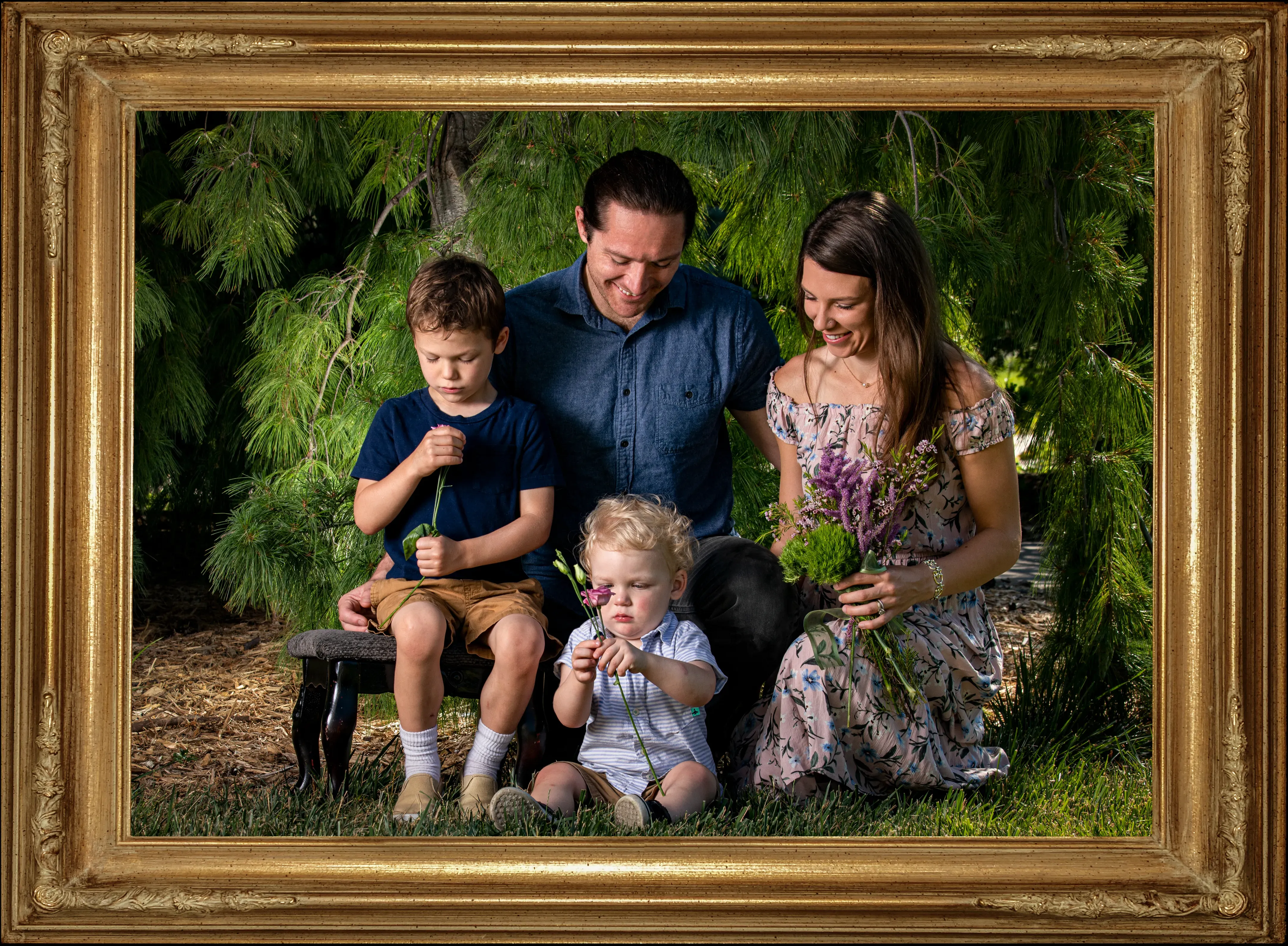 The Cartier Family posed together celebrating their two children. Husband and wife over looking their young boys.