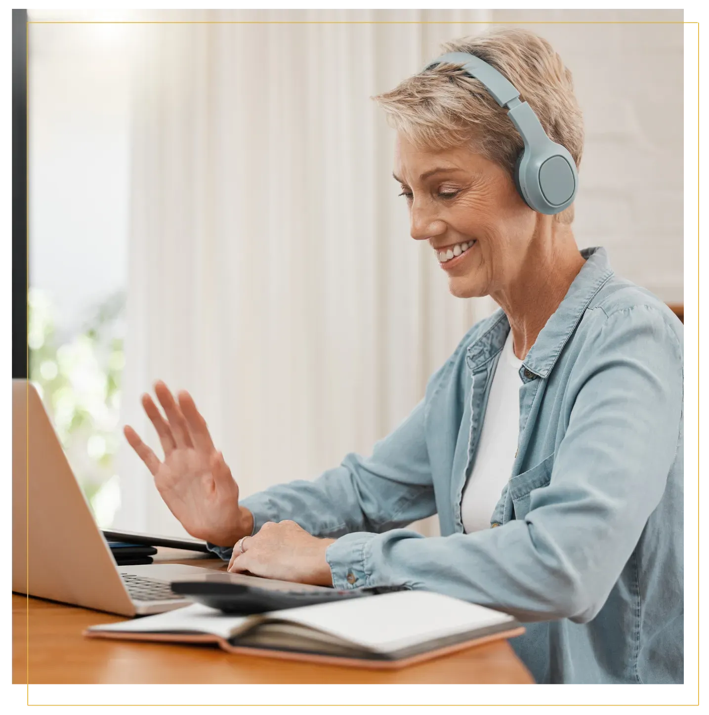 Smiling woman wearing headphones on a video call with a notebook getting help