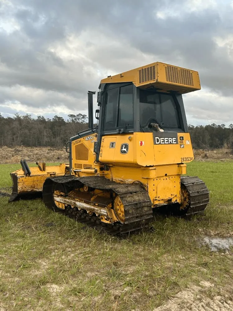 <alt=“After heavy equipment pressure washing in Hurley, Jackson County, Mississippi showing clean John Deere bulldozer with fully restored tracks and exterior.”