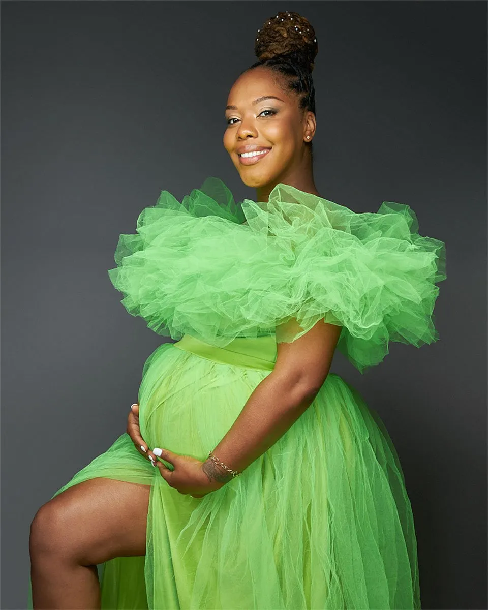 Maternity portrait of woman in a ruffled lime green dress posed in front of a grey backdrop