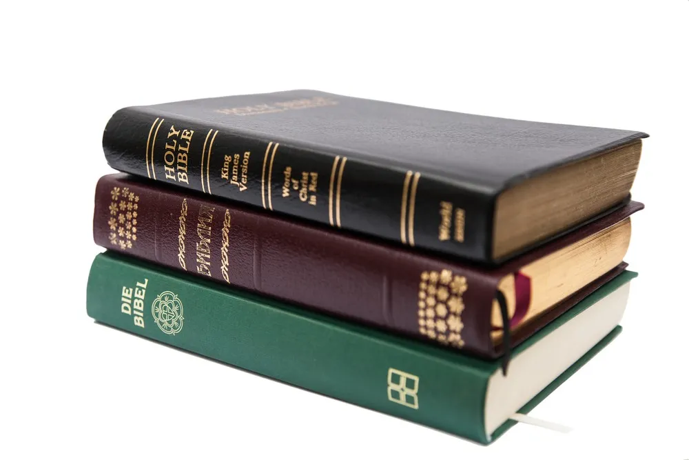 A stack of Bibles and Quran on a white background.