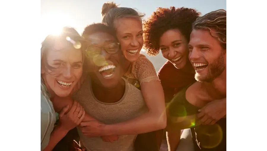 A warm, engaging image of a group of diverse people of various ages laughing and conversing in a cozy setting.