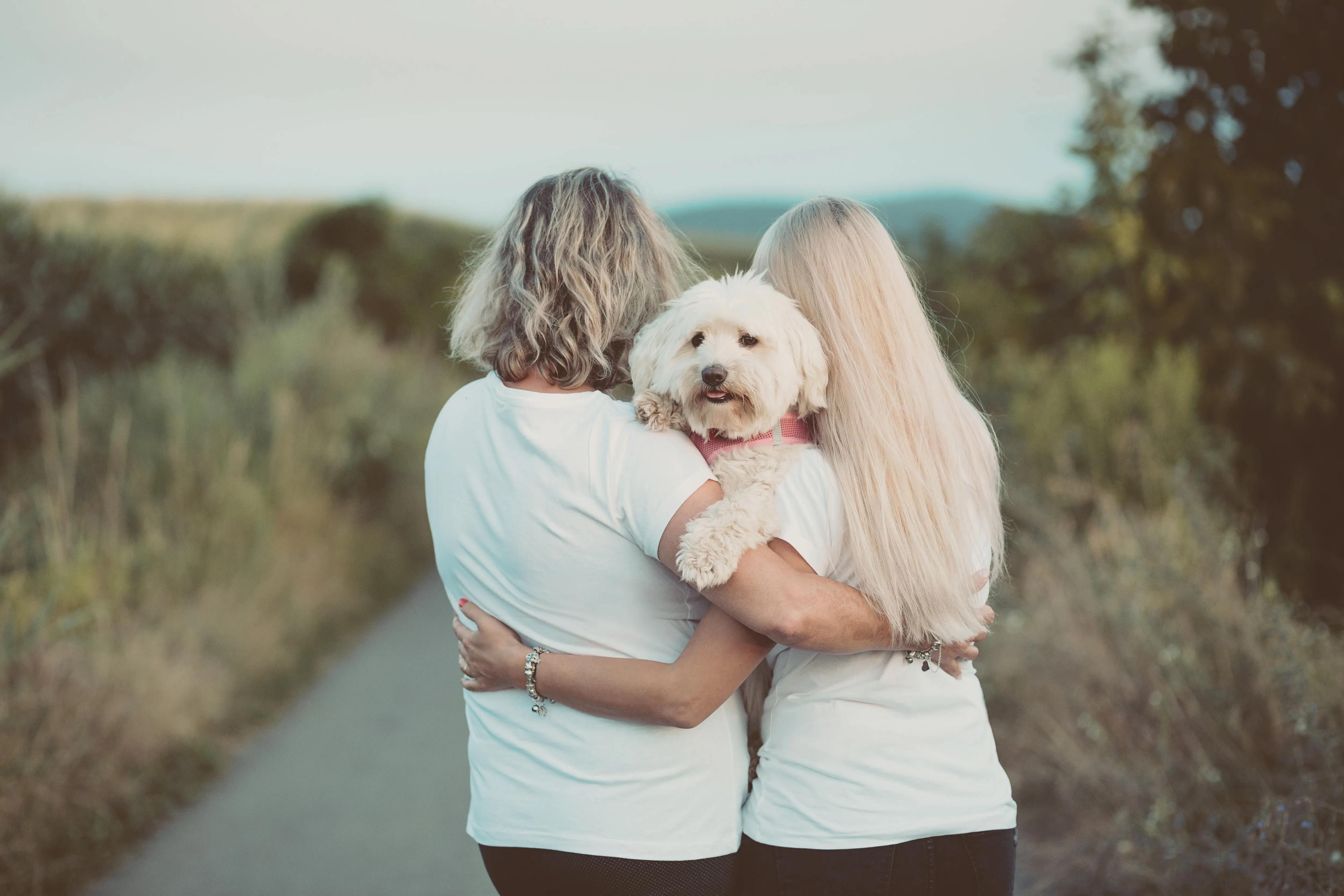 backs of mother and daughter with dog facing camera between the heads