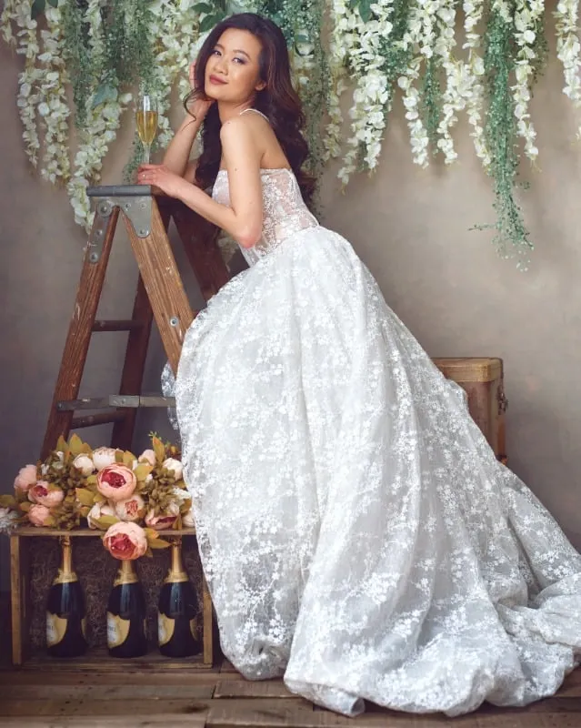 Bridal portrait of Asian woman in a wedding dress posed on a ladder