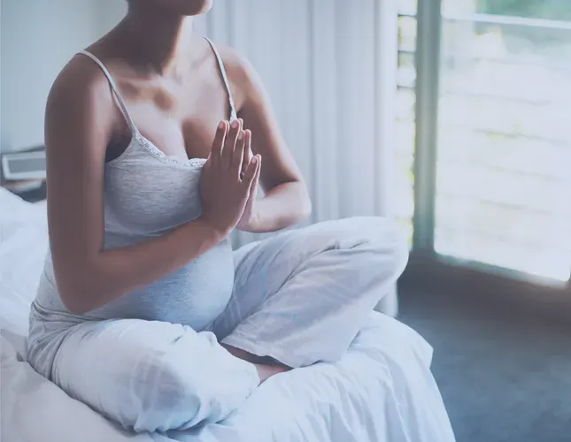 an image of a pregnant woman meditating, with a calm background